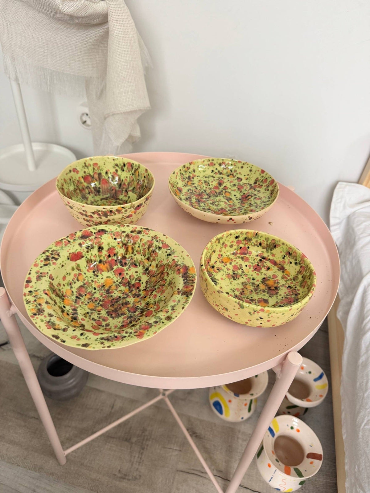 Four speckled yellow bowls on a pink table