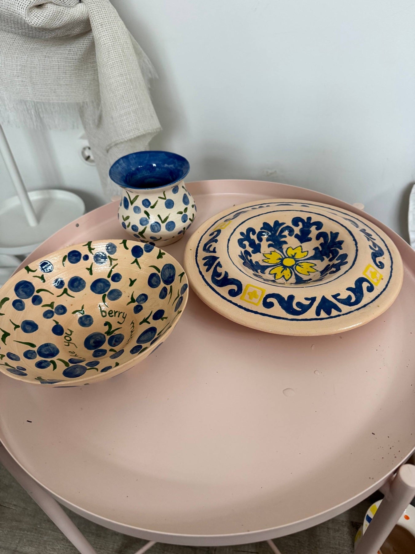 Hand-painted bowl and plate in blue and yellow on a pink studio table