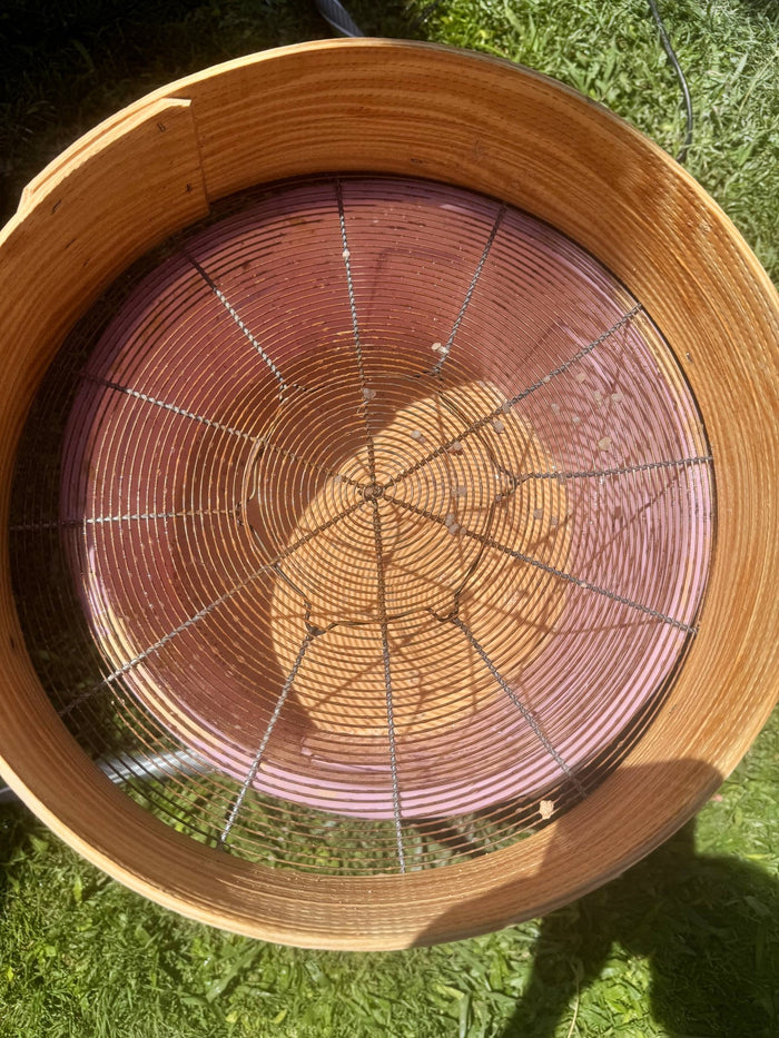 Clay being sieved by hand through a round sieve