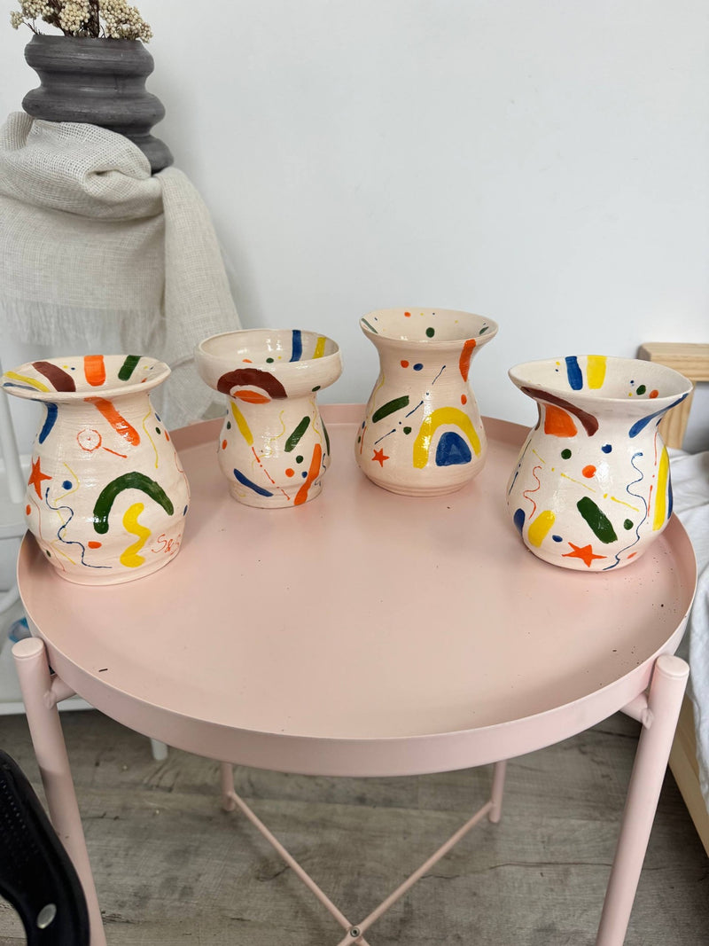 Four hand-painted vases on a pink table in the studio